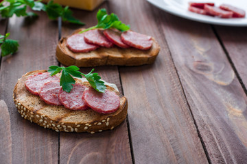 homemade sandwich with rye bread sliced salami and parsley on wooden rustic background