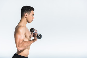 side view of shirtless mixed race man training with dumbbells on white