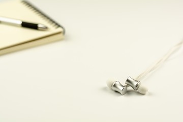 earphone with diary book and pen on white desk background.