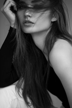 Fashion minimalist dark portrait of brunette female model on grey background. stylish clothing, black and white concept