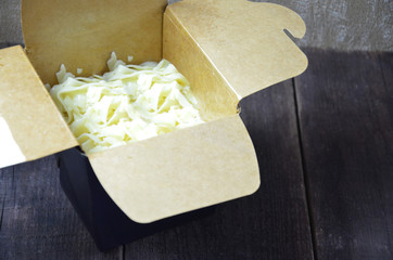 Chinese noodles in black paper box and chopsticks in hand Wok noodles. on the wooden background