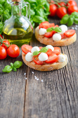 Bruschetta with cherry tomatoes and mozzarella on rustic wooden table, selective focus, copy space.