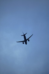 Aviation Industry - An air plane with tilted wings landing down posture in a cloudy dark blue background - Travel concept