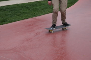 young skateboarder legs riding skateboard at skatepark. With copy space for text.