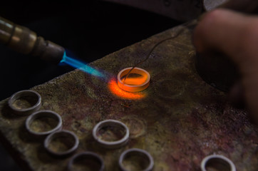Fototapeta na wymiar Craft jewelery making with professional tools. Macro shot. A handmade jeweler process, manufacture of jewellery. Melting metal