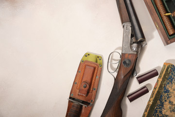 Hunting concept with shotgun, knife and ammunition for hunting arranged on light background.