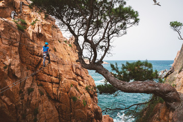 Girl climbing on a Via ferrata, Sant Feliu de Guixols, Catalunya, Spain (Via ferrata Cala de Molí)