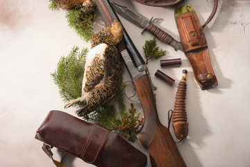 Hunting concept with ptarmigan, shotgun, fir-tree branches and ammunition for hunting arranged on...