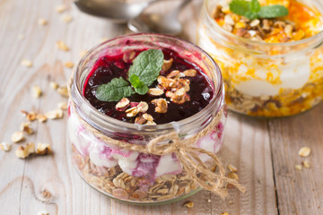 Yogurt, granola, black currant and  sea buckthorn jam in glass jars