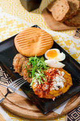 Delicious breakfast with boiled eggs, pumpkin puree, lettuce, cheese and fresh bread on a black plate on a yellow set on a wooden table in a restaurant. Close up. Space