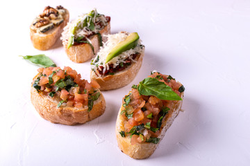 Set of assorted bruschetta with various toppings for holiday on white background. Top view. Party food concept.