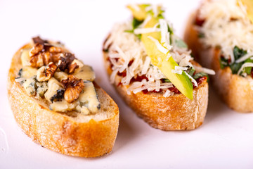 Set of assorted bruschetta with various toppings for holiday on white background. Close-up. Party food concept.