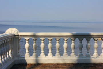 White balustrade fence facing sea or lake shore. Scenic horizon view from vacation house property 