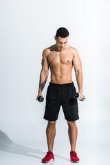 handsome mixed race man holding dumbbells and looking down on white