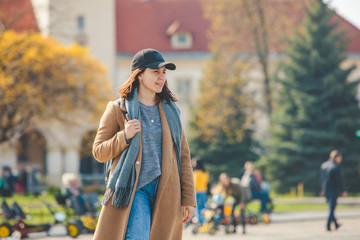 young pretty fashionable woman walking in brown coat by street