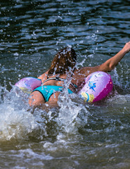 a woman in a bright swimsuit swim away with a water bubble, creating a lot of big splashes