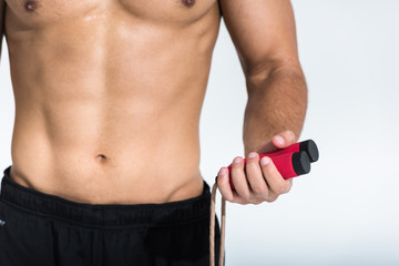 cropped view of man with muscular torso holding jump rope on white