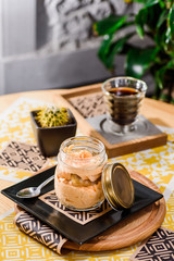 Coffee and traditional Italian dessert -tiramisu, in a jar on a wooden table in the restaurant. Beautiful pumpkin tiramisu serving in a restaurant on a yellow background. close up