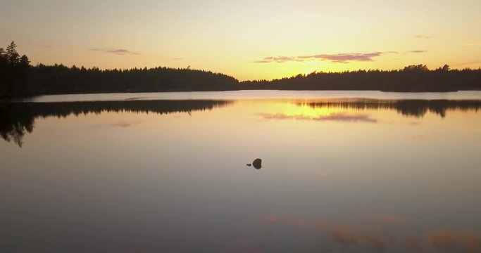 Flight over forest lake with old wooden jetty in sunset a beautiful spring evening in Sweden