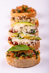 Set of assorted bruschetta with various toppings for holiday on white background. Macro. Party food concept.