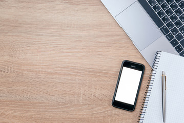 Flat lay of wooden office desk with laptop, smartphone, pen and notebook with copy space background.