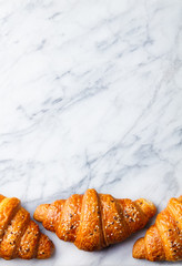 Croissants on marble table. French traditional pastry. Top view. Copy space.