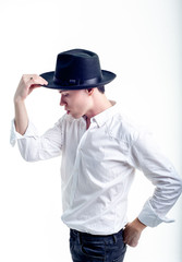 The guy in the white shirt and hat on a white background, the guy holds his hat with one hand, posing in the studio - isolated