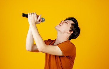 Karaoke man singing a song into a microphone, on a yellow background. A funny man holds a...