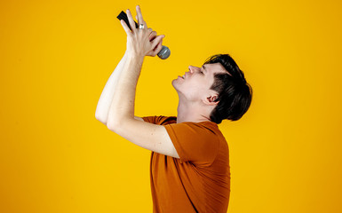 Karaoke man singing a song into a microphone, on a yellow background. A funny man holds a microphone in his hand at the karaoke singer singing a song! Pivets on a yellow background