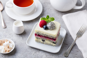 Berry, poppy seed layered cake on white plate. Grey background.
