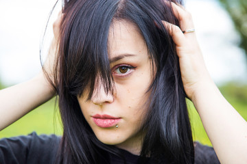 Fototapeta premium Close up portrait of beautiful young woman posing with hands on her head, hair over face, dark mood