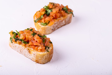 Tasty savory tomato Italian appetizers, or bruschetta, on slices of toasted baguette garnished with basil.