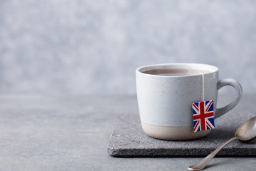 Tea in mug with British flag tea bag label. Grey background. Copy space.