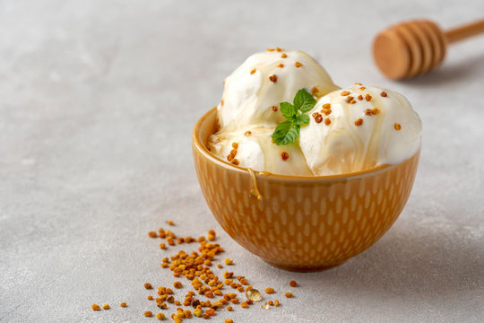 Tasty ice cream with bee pollen and honey in bowl on table