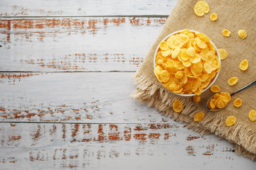 Golden flakes in a cup on burlap, on a light wooden table, next to a spoon. Rustic country style....