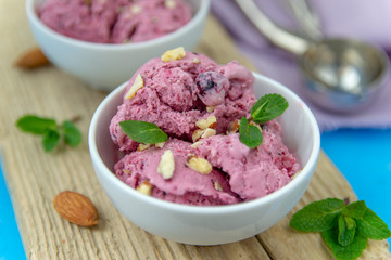 Ice cream with berries. Ice cream balls in a white bowl with nuts and mint.