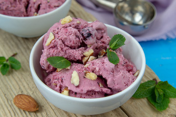 Ice cream with berries. Ice cream balls in a white bowl with nuts and mint.