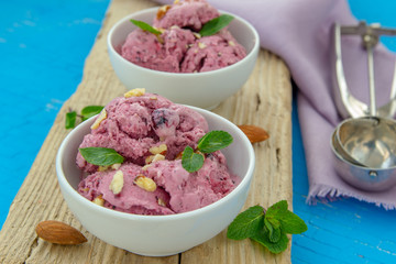 Ice cream with berries. Ice cream balls in a white bowl with nuts and mint.