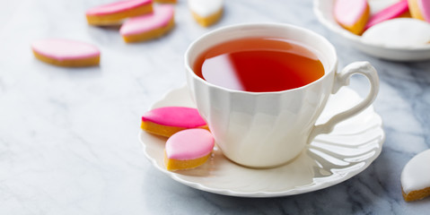 Cup of tea with calissons, traditional French Provence sweets on marble background. Copy space.