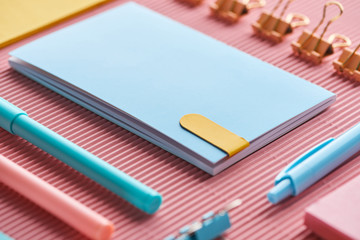selective focus of notebook and colorful stationery supplies on pink