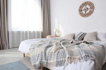Bed with pillows and plaid in modern room interior