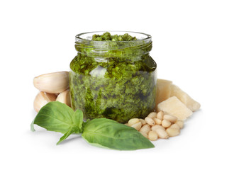 Jar of tasty pesto sauce and ingredients isolated on white