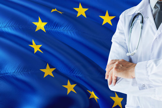 European Doctor standing with stethoscope on European Union flag background. National healthcare system concept, medical theme.