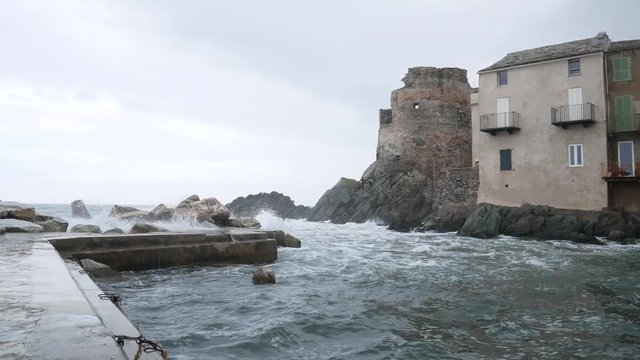 Erbalunga, Cap-Corse, Corsica, France, Europe - april 22 2019: Large waves batter on the harbor of Erbalunga (fishing village). The stormy sea on Torra d'Erbalunga, tower from the 16th century