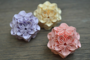 Purple, yellow and pink origami kusudama flower on wooden background