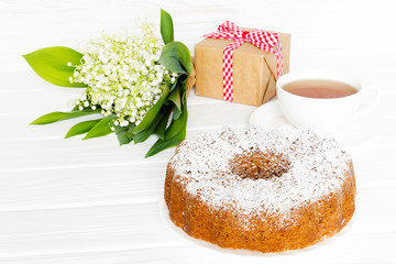 Still life with Bundt Cake, tea and flower with gift. Greeting concept