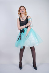 Naklejka premium charming blonde teenager girl in a bright dress with a transparent glass of water on a white background in the Studio