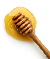 Top view of wooden honey dripper in the honey puddle