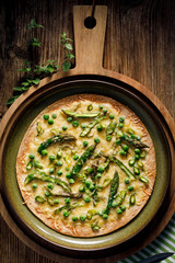 Tortilla Pizza with green asparagus, peas and cheese on a rustic, wooden table, top view. Vegetarian food. 