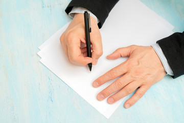 A pen in a man's hand. White sheet of paper. Signing a document.